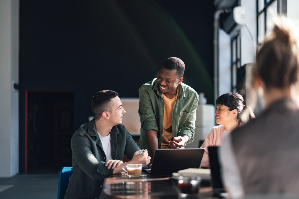 Young professionals engaging in a collaborative work session in a sunlit and trendy co-working environment.